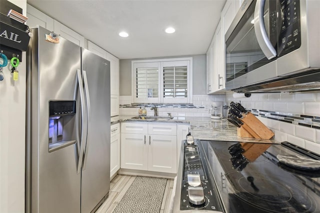 kitchen featuring light stone counters, tasteful backsplash, white cabinets, stainless steel appliances, and light tile flooring