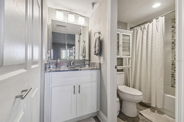 full bathroom with shower / tub combo, a textured ceiling, toilet, and vanity with extensive cabinet space