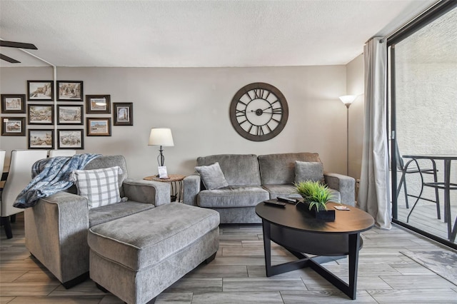 living room featuring ceiling fan, a textured ceiling, and light hardwood / wood-style floors