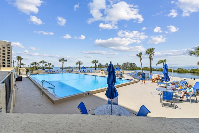 view of pool featuring a water view and a patio