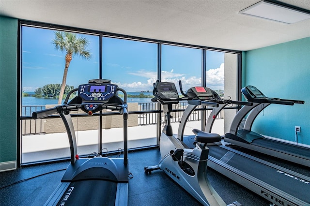 workout area with a water view and a textured ceiling