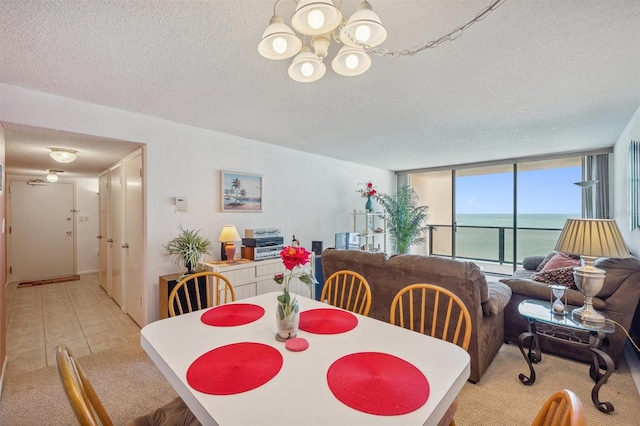 dining room featuring a water view, a textured ceiling, an inviting chandelier, and light tile floors