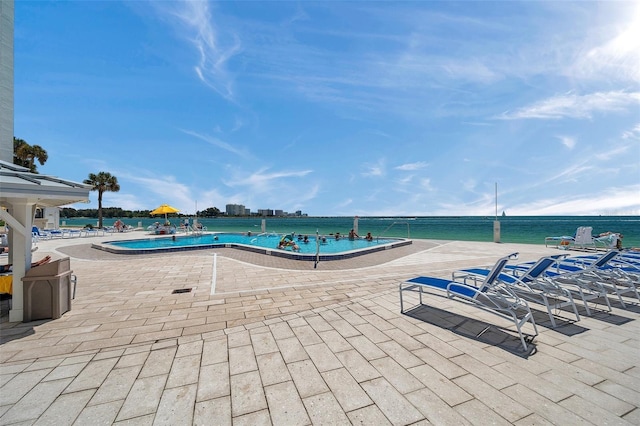 view of swimming pool with a patio area and a water view