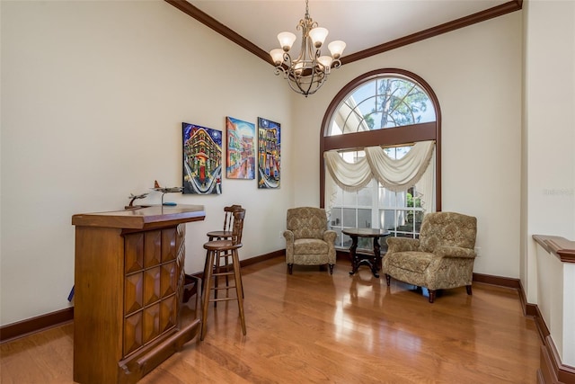 sitting room featuring wood-type flooring, crown molding, and an inviting chandelier