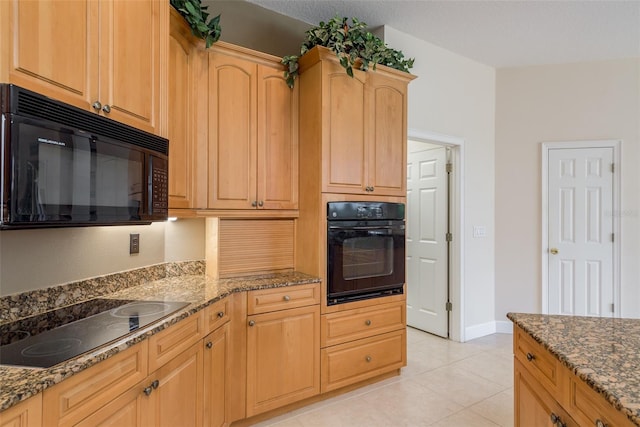 kitchen featuring dark stone counters, light tile flooring, and black appliances