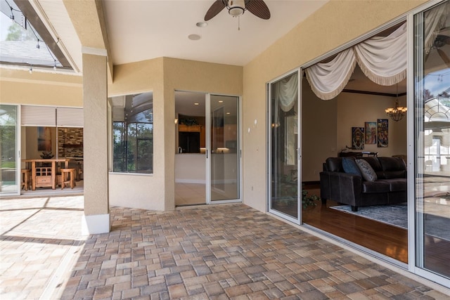 exterior space featuring ceiling fan with notable chandelier