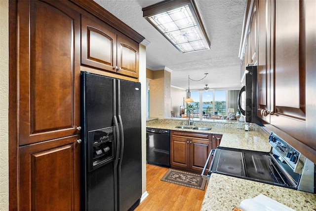 kitchen with black appliances, light hardwood / wood-style floors, sink, and a textured ceiling