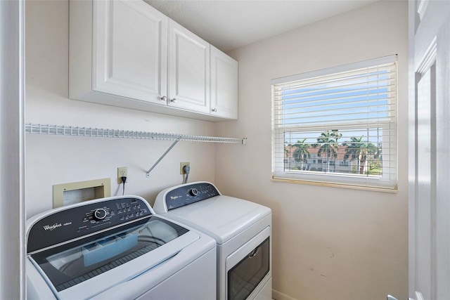 washroom with washer and dryer and cabinets