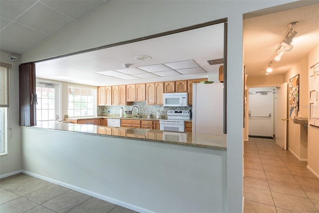 kitchen featuring white appliances, light tile flooring, light stone counters, tasteful backsplash, and track lighting