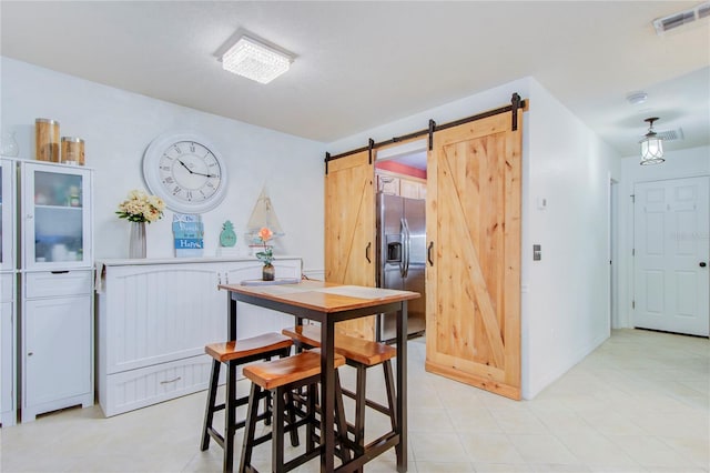 dining room featuring a barn door and light tile flooring