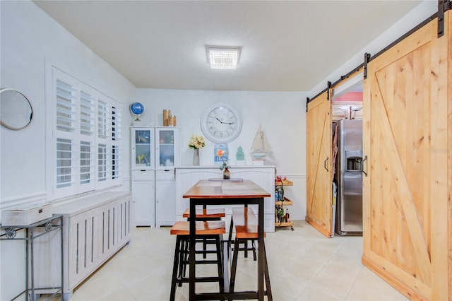 dining area with light tile flooring and a barn door