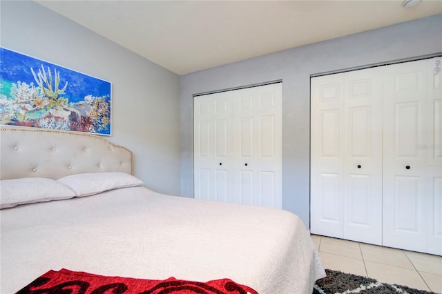 bedroom with multiple closets and light tile floors