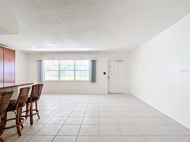 interior space featuring a dry bar, baseboards, a textured ceiling, and light tile patterned flooring