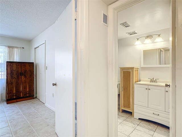 bathroom with vanity, a textured ceiling, and tile patterned flooring