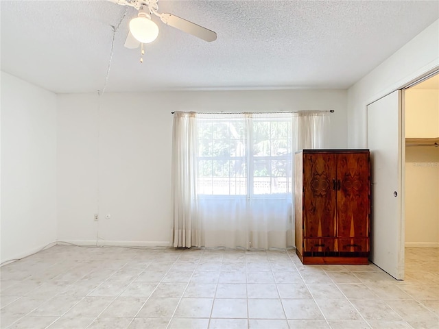 unfurnished bedroom featuring ceiling fan, light tile patterned flooring, a textured ceiling, and a closet