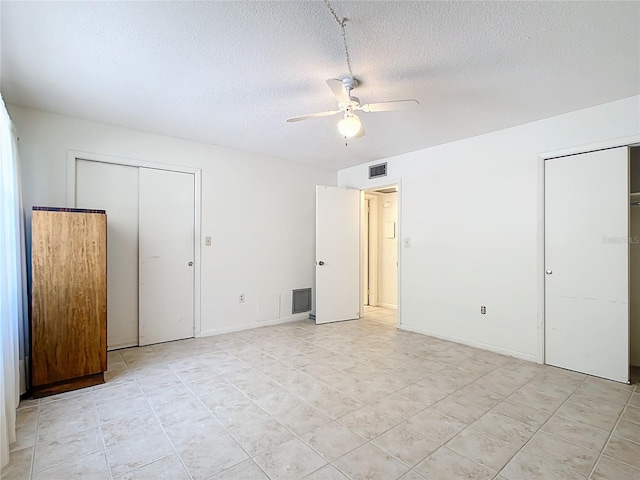 unfurnished bedroom with ceiling fan, a textured ceiling, multiple closets, and light tile patterned floors