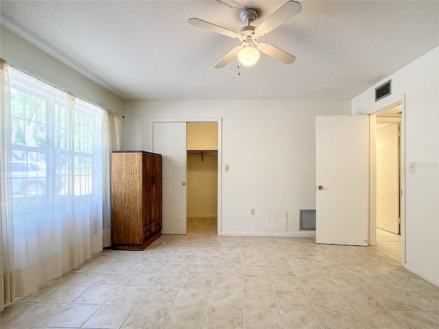 unfurnished bedroom with a ceiling fan, visible vents, and a textured ceiling