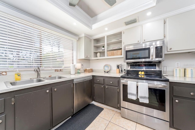 kitchen with sink, white cabinets, stainless steel appliances, light tile patterned floors, and crown molding