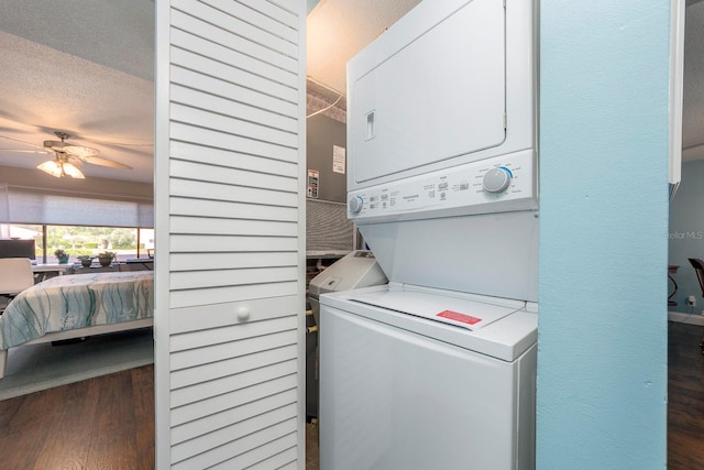 laundry area with a textured ceiling, ceiling fan, dark hardwood / wood-style floors, and stacked washing maching and dryer