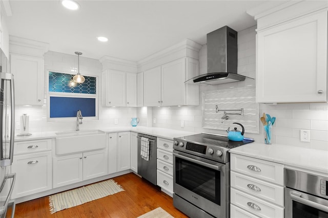 kitchen with backsplash, pendant lighting, wall chimney range hood, and stainless steel appliances