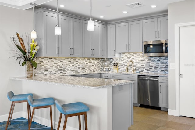 kitchen with hanging light fixtures, tasteful backsplash, gray cabinetry, and stainless steel appliances