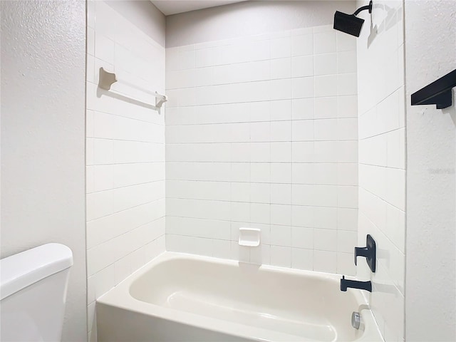 bathroom featuring tiled shower / bath combo and toilet