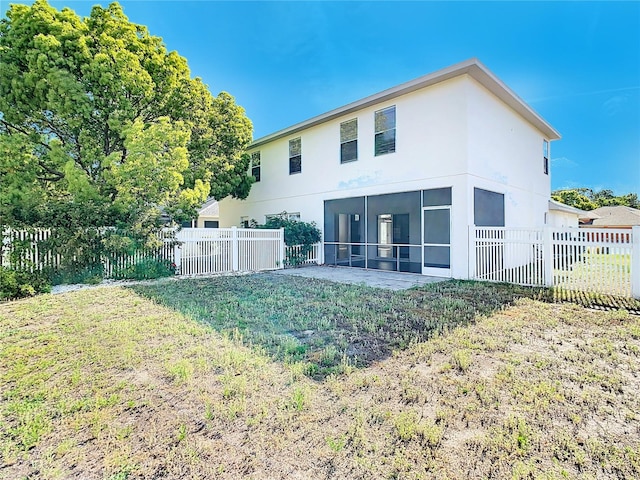 back of property with a patio area, a sunroom, and a lawn