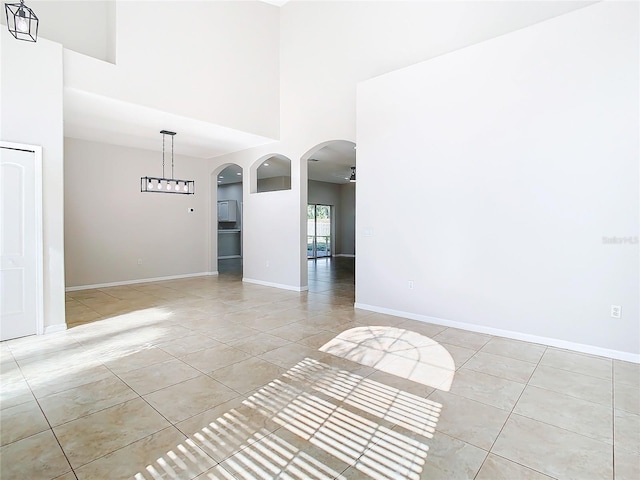 spare room featuring ceiling fan, a towering ceiling, and light tile floors