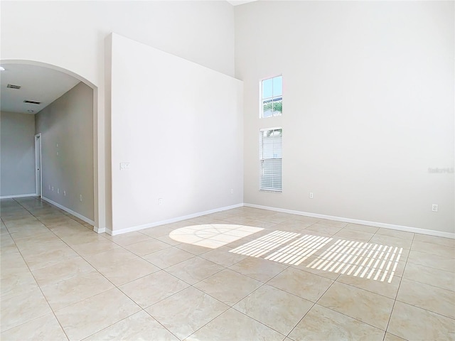 unfurnished room with light tile floors and a high ceiling