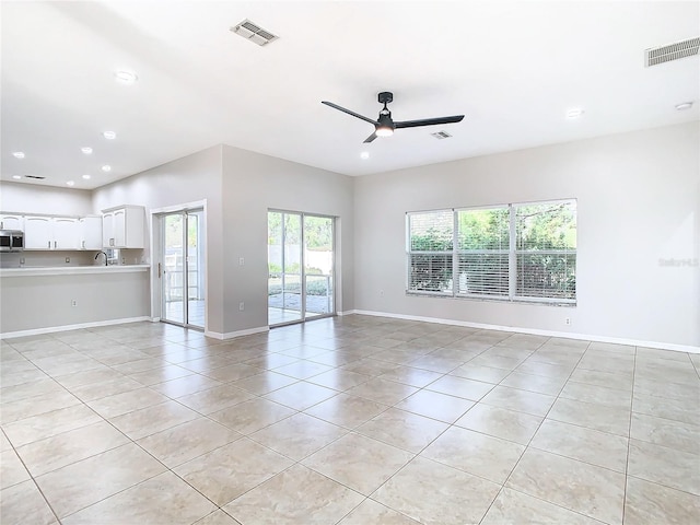 unfurnished living room featuring sink, ceiling fan, and light tile floors