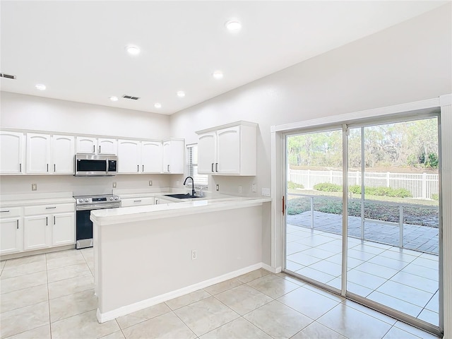 kitchen featuring appliances with stainless steel finishes, kitchen peninsula, light tile floors, and white cabinetry