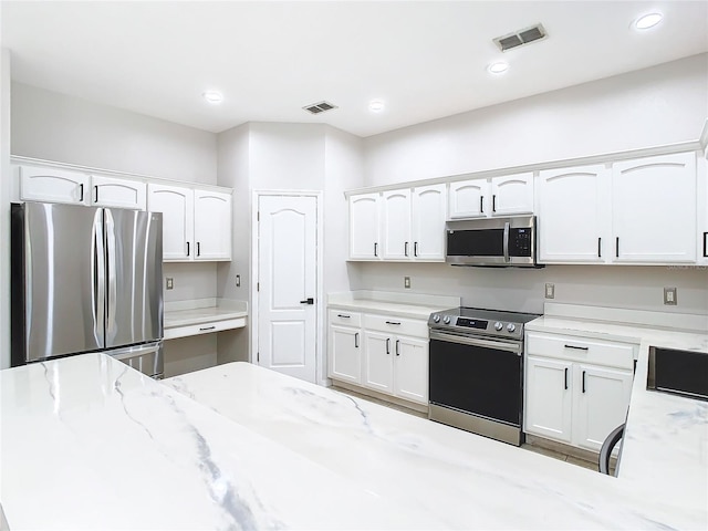 kitchen with white cabinets, sink, stainless steel appliances, and light stone counters