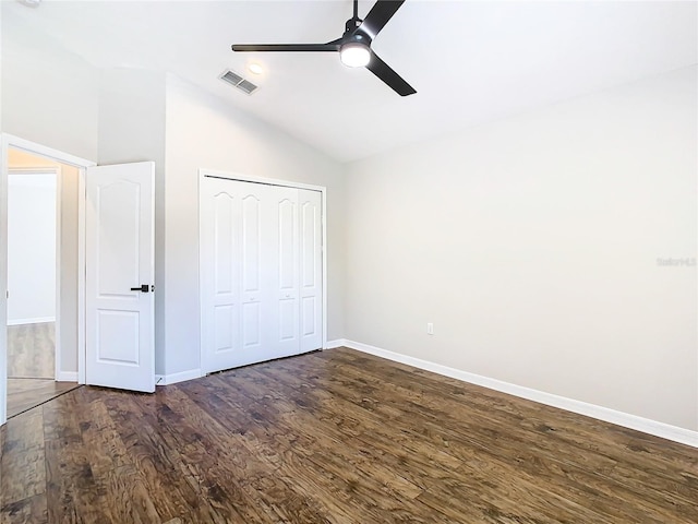 unfurnished bedroom with vaulted ceiling, ceiling fan, a closet, and dark wood-type flooring