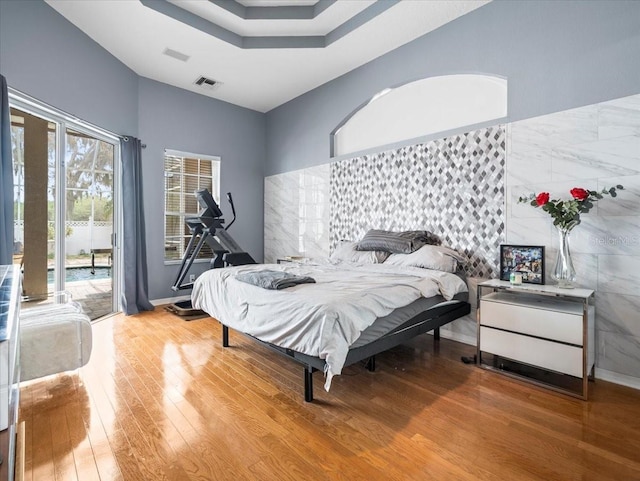 bedroom with access to outside, light hardwood / wood-style floors, and multiple windows