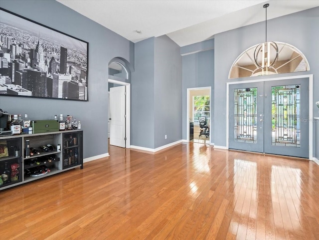 foyer featuring light hardwood / wood-style flooring, french doors, and a towering ceiling