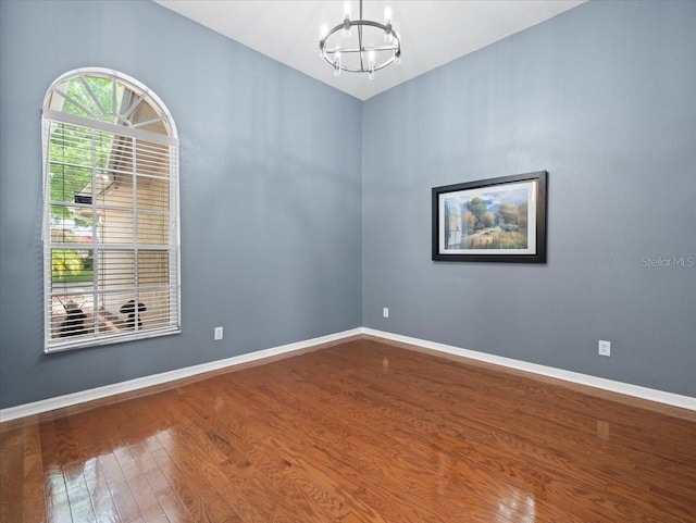 empty room with dark hardwood / wood-style floors and an inviting chandelier