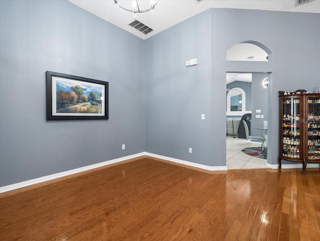 spare room featuring light hardwood / wood-style floors and high vaulted ceiling