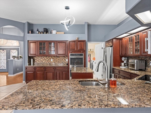 kitchen with light stone counters, appliances with stainless steel finishes, tasteful backsplash, and sink