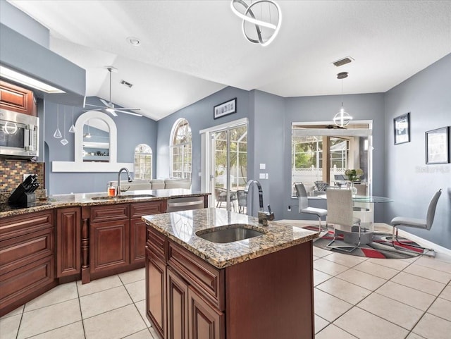 kitchen with light stone counters, sink, hanging light fixtures, stainless steel appliances, and vaulted ceiling