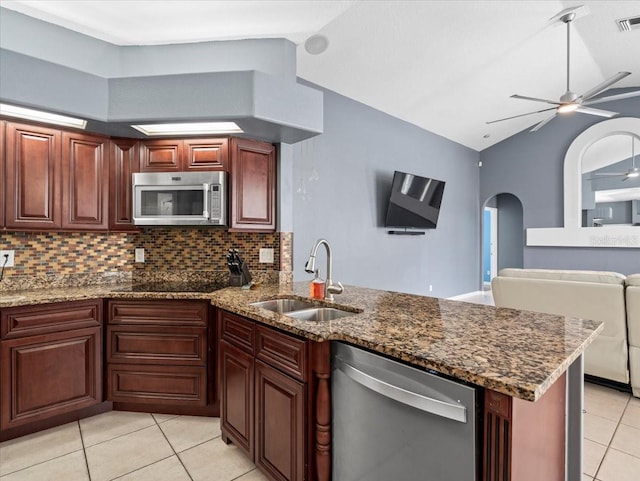 kitchen featuring appliances with stainless steel finishes, ceiling fan, sink, dark stone counters, and vaulted ceiling