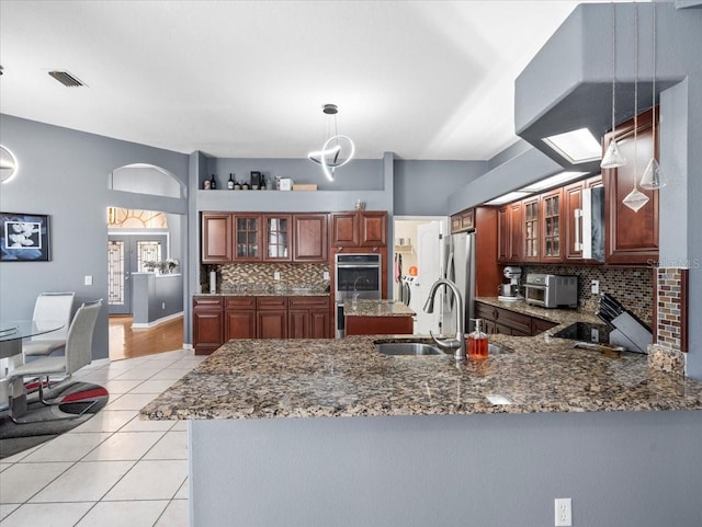 kitchen with stone countertops, stainless steel appliances, tasteful backsplash, sink, and pendant lighting