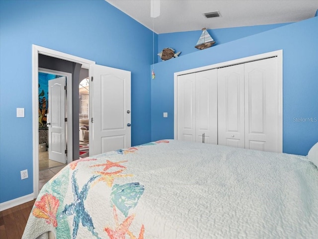 bedroom featuring a closet, ceiling fan, dark wood-type flooring, and vaulted ceiling