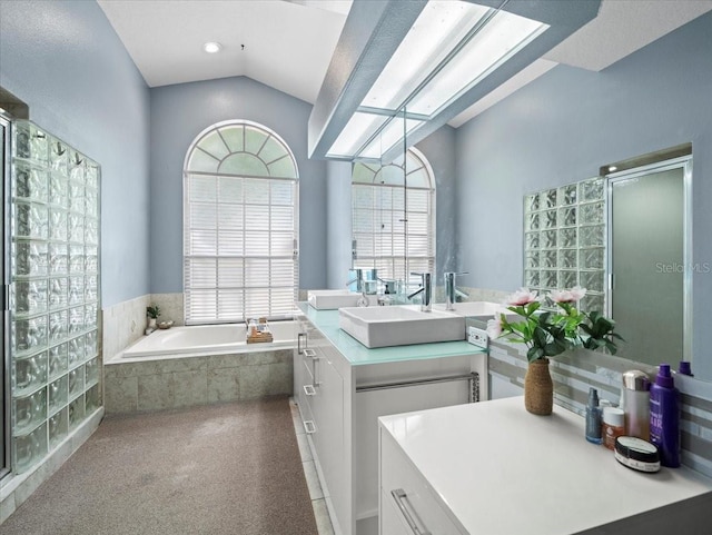 bathroom featuring vanity, lofted ceiling with skylight, and tiled bath