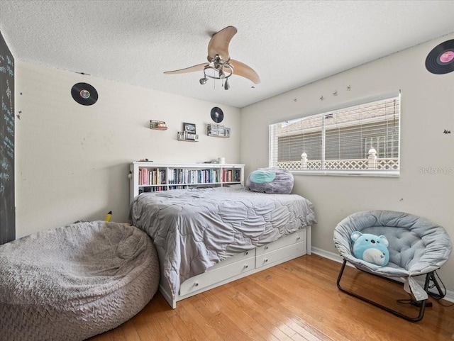 bedroom featuring ceiling fan, a textured ceiling, and light wood-type flooring