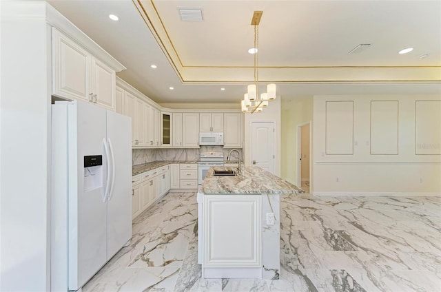 kitchen featuring white appliances, decorative light fixtures, light stone countertops, an island with sink, and white cabinets