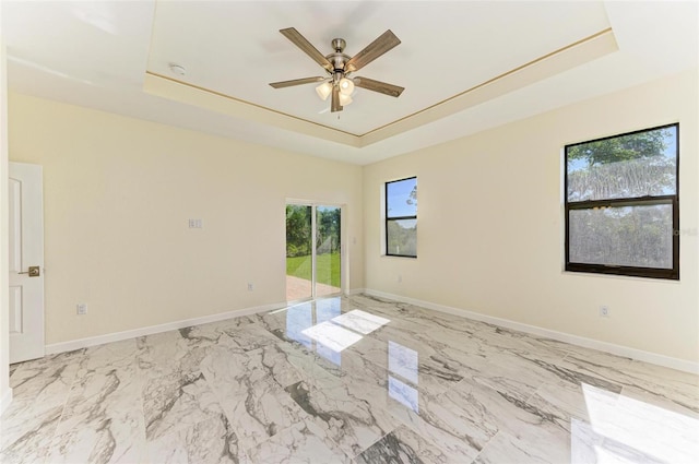 spare room featuring ceiling fan and a raised ceiling