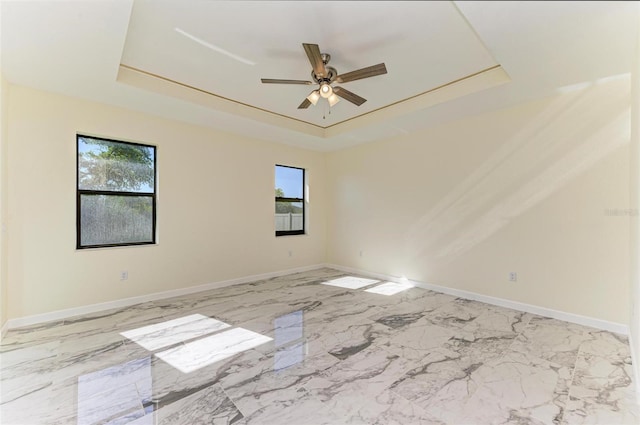 empty room featuring plenty of natural light, a tray ceiling, and ceiling fan