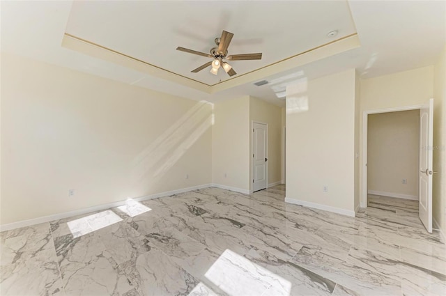 empty room featuring a tray ceiling and ceiling fan