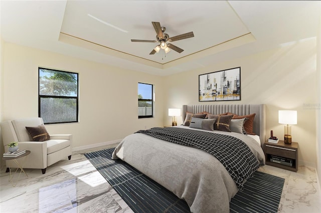 bedroom featuring a raised ceiling, multiple windows, and ceiling fan