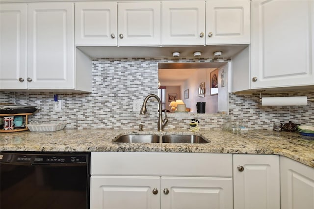 kitchen featuring tasteful backsplash, light stone counters, sink, black dishwasher, and white cabinets